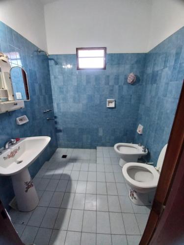uma casa de banho em azulejos azuis com 2 WC e um lavatório em CASA ANTONIA em Embalse