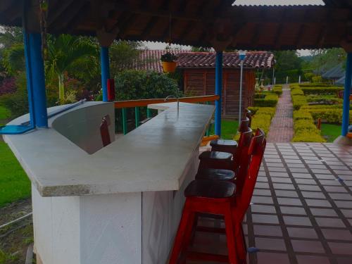 a bar with a row of chairs and an umbrella at Finca Hotel El Ocaso in Quimbaya