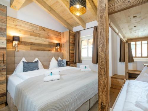 a bedroom with a large white bed and wooden walls at Tauernlodge Liz in Mühlbach am Hochkönig