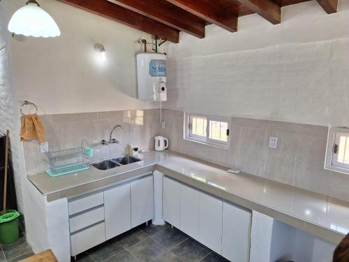 una cocina con armarios blancos y fregadero en Mercedario Aparts en Barreal