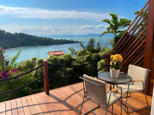 uma mesa e cadeiras num deque com vista para a água em Mar de Bougainville em Governador Celso Ramos