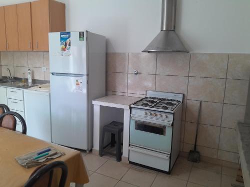 een keuken met een fornuis, een koelkast en een tafel bij Bragado Apart in Bragado
