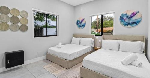 una camera con due letti e una TV e due finestre di Waterfront Mansion The GlamHomes a North Miami Beach
