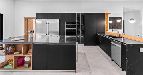 una cucina con armadi neri e frigorifero in acciaio inossidabile di Waterfront Mansion The GlamHomes a North Miami Beach