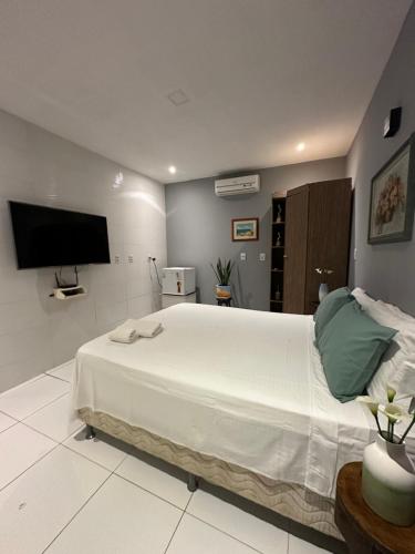 a bedroom with a large white bed and a flat screen tv at Chalé Betel in Galinhos