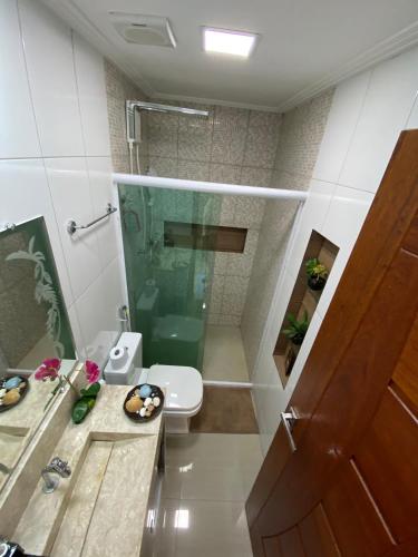 a bathroom with a toilet and a glass shower at Triplex Curumim - Zohra in Itaparica