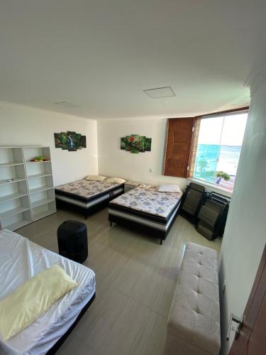 um quarto com três camas e uma janela em Triplex Curumim - Zohra em Itaparica