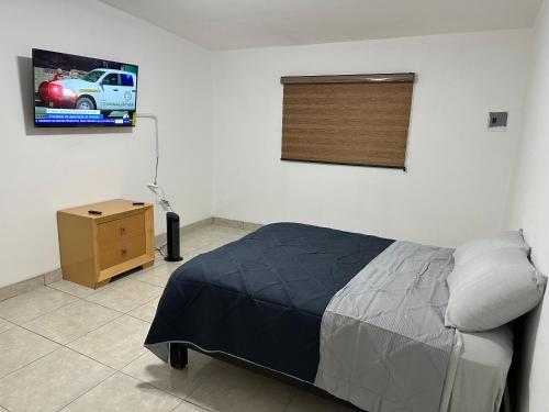 um quarto com uma cama e uma televisão na parede em Habitaciones ENMA em Ciudad Juárez
