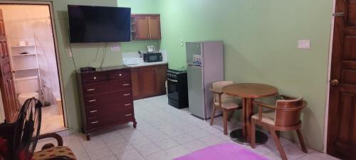 a small kitchen with a table and a refrigerator at Wizzy Apartment White River in Ocho Rios