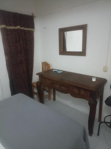 einen Schreibtisch in einem Zimmer mit einem Bett und einem Spiegel in der Unterkunft Apartamento Vacacional con A/C in Cozumel