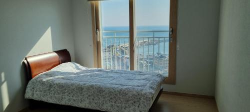 a bedroom with a bed and a large window at Gangneung Sacheon beach Happy House in Gangneung