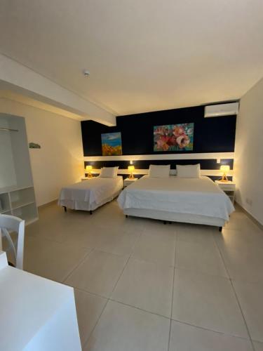 a bedroom with two beds and two tables and two lamps at Hotel Port Louis in Caraguatatuba