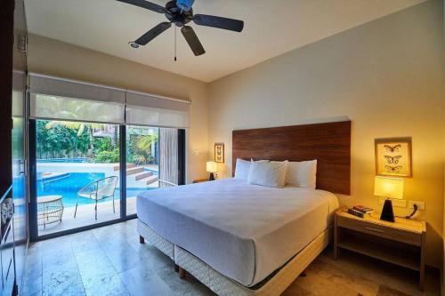 a bedroom with a bed and a balcony with a pool at Zen Oasis Swim Up Condo Pool W Tiki Hut Bar + Gym in Tulum