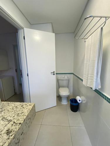 a bathroom with a white toilet and a door at Hotel Port Louis in Caraguatatuba