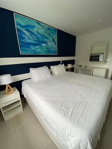 a bedroom with a white bed with a blue wall at Hotel Port Louis in Caraguatatuba