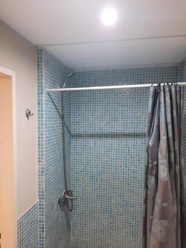 y baño con ducha de azulejos azules. en Monoambiente en Muñiz en 