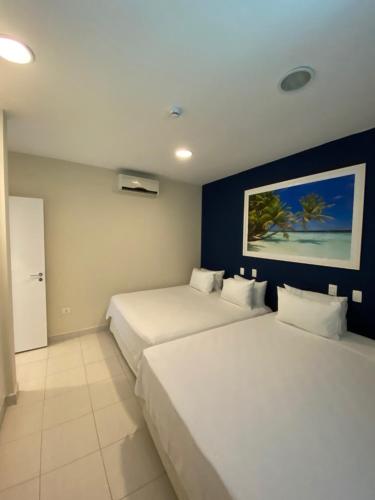 two beds in a room with blue walls at Hotel Port Louis in Caraguatatuba
