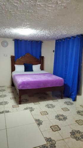 a bedroom with a purple bed with blue curtains at Wizzy Apartment White River in Ocho Rios