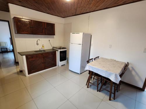 a kitchen with a refrigerator and a table in it at Pousada Bartrô in Rio das Ostras