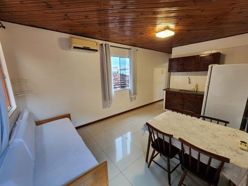 a kitchen with a table and chairs and a refrigerator at Pousada Bartrô in Rio das Ostras