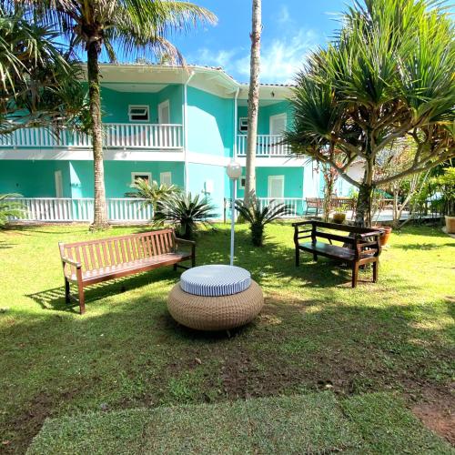 two benches and a table in front of a house at Hotel Port Louis in Caraguatatuba
