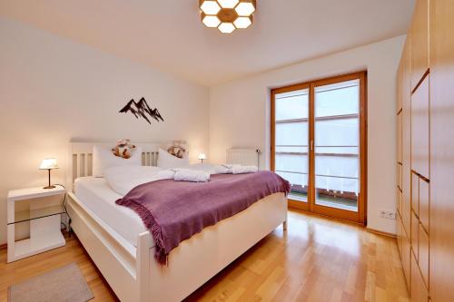 een slaapkamer met een groot wit bed en een raam bij BergLiebe in Garmisch-Partenkirchen