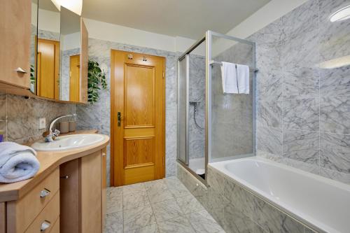 een badkamer met een bad, een wastafel en een douche bij BergLiebe in Garmisch-Partenkirchen