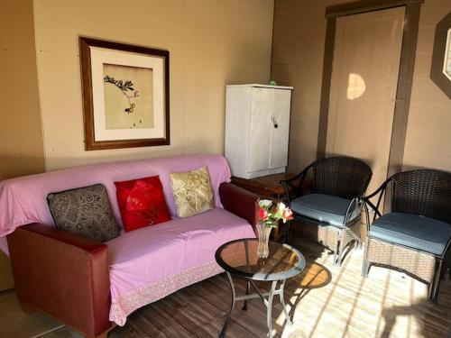 sala de estar con sofá rosa y 2 sillas en Sun Guest House Pahrump, en Pahrump