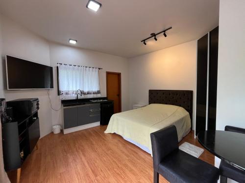 Dormitorio con cama, escritorio y TV en Jardim do Sol Residence, en Palhoça