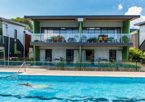 a person swimming in a pool in front of a house at Marion Holiday Park in Adelaide