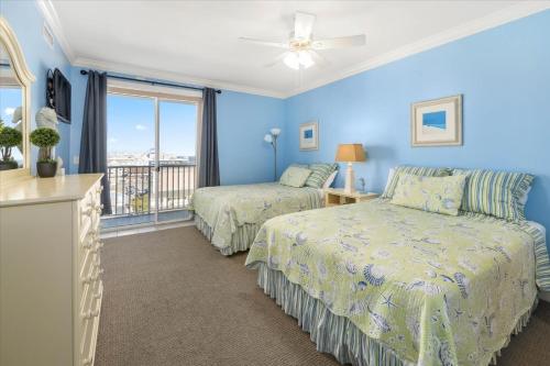 a blue bedroom with two beds and a window at 3 BR Belmont Towers on Boardwalk: Ocean & Bay Views in Ocean City