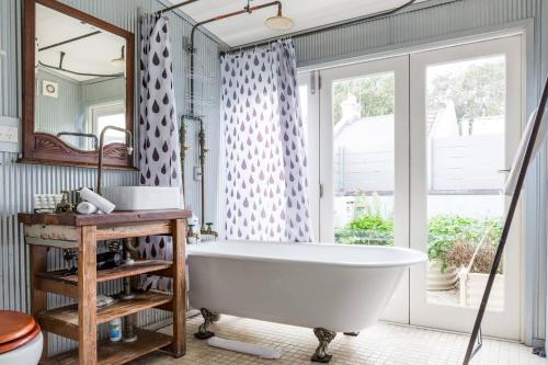 a bathroom with a white tub and a mirror at Urban Farmhouse Flair - Surry Hills Terrace Serenity in Sydney