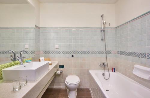 a bathroom with a sink and a tub and a toilet at Village Hotel Albert Court by Far East Hospitality in Singapore