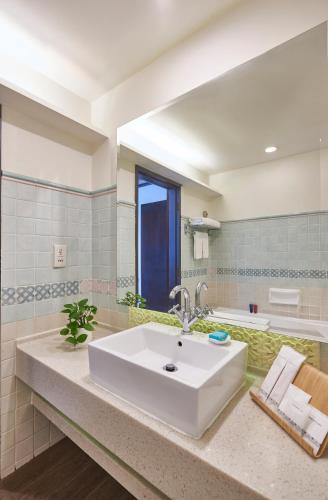 a bathroom with a sink and a large mirror at Village Hotel Albert Court by Far East Hospitality in Singapore