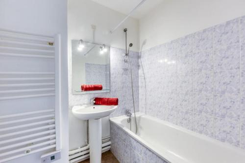 een witte badkamer met een wastafel en een bad bij Appartement F2 haut de Montreuil in Montreuil