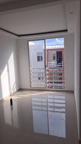 Habitación blanca con ventana grande y balcón con una persona. en Apartamento cómodo y económico en Barranquilla