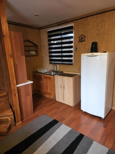 a kitchen with a white refrigerator and a sink at Cabaña Equipada Sector Residencial in Valdivia