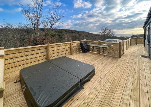 a wooden deck with a table and a desk on it at Shear Barn Holiday Park in Hastings