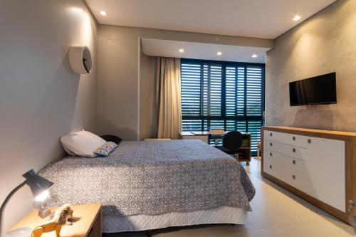 a bedroom with a bed and a desk and a television at Alto padrão piscina aquecida em Balneário Camboriú in Balneário Camboriú