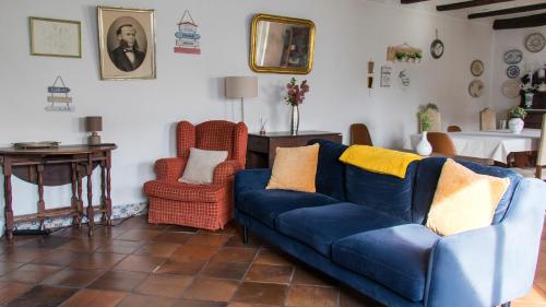 a living room with a blue couch and two chairs at Casa da Paz in Labrugeira
