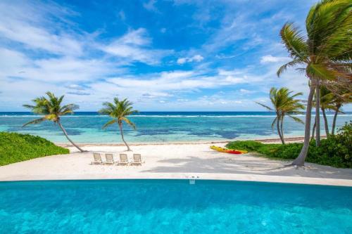 a swimming pool in front of a beach with palm trees at Ocean Kai home in Driftwood Village