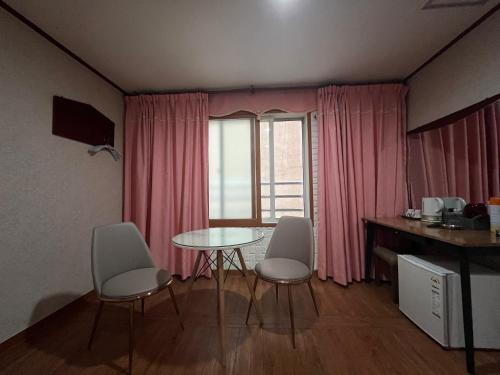 a dining room with a table and chairs and a window at Oreum Motel in Jeju