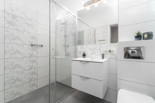 a white bathroom with a shower and a sink at Comfortable apartment near the sea, Pobierowo in Pobierowo