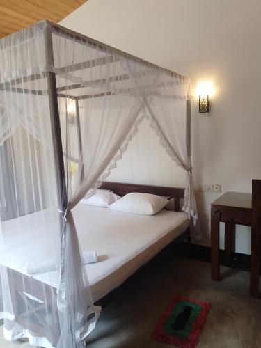 a bedroom with a canopy bed with white curtains at Unawatuna Backpacker Lodge in Unawatuna