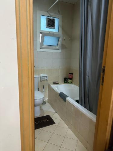 a bathroom with a toilet and a bath tub and a window at Fully Furnished Masteroom with attached washroom in Dubai