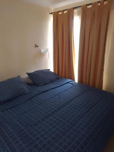 un letto blu in una camera da letto con finestra di Apart Hotel Melipilla a Melipilla