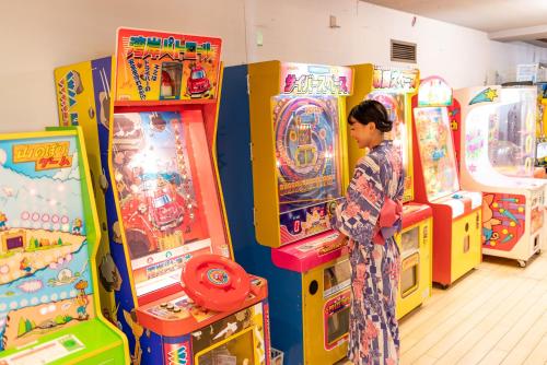 a woman standing in front of arcade games at Daitokan in Kusatsu