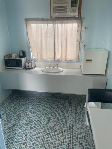 a bathroom with a sink and a window with a microwave at Springsure Hotel Motel in Springsure