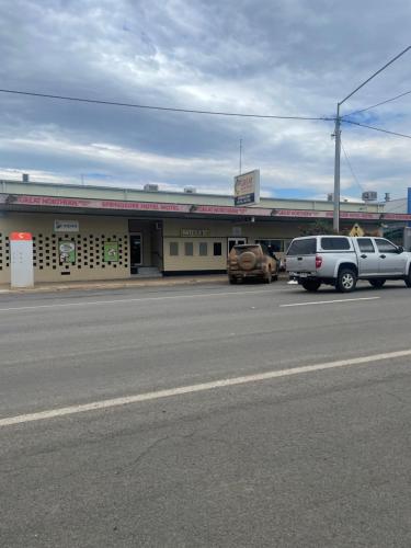 a parking lot with cars parked in front of a store at Springsure Hotel Motel in Springsure