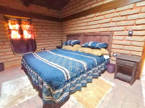 a large bed in a room with a brick wall at Cabaña El Fresno 